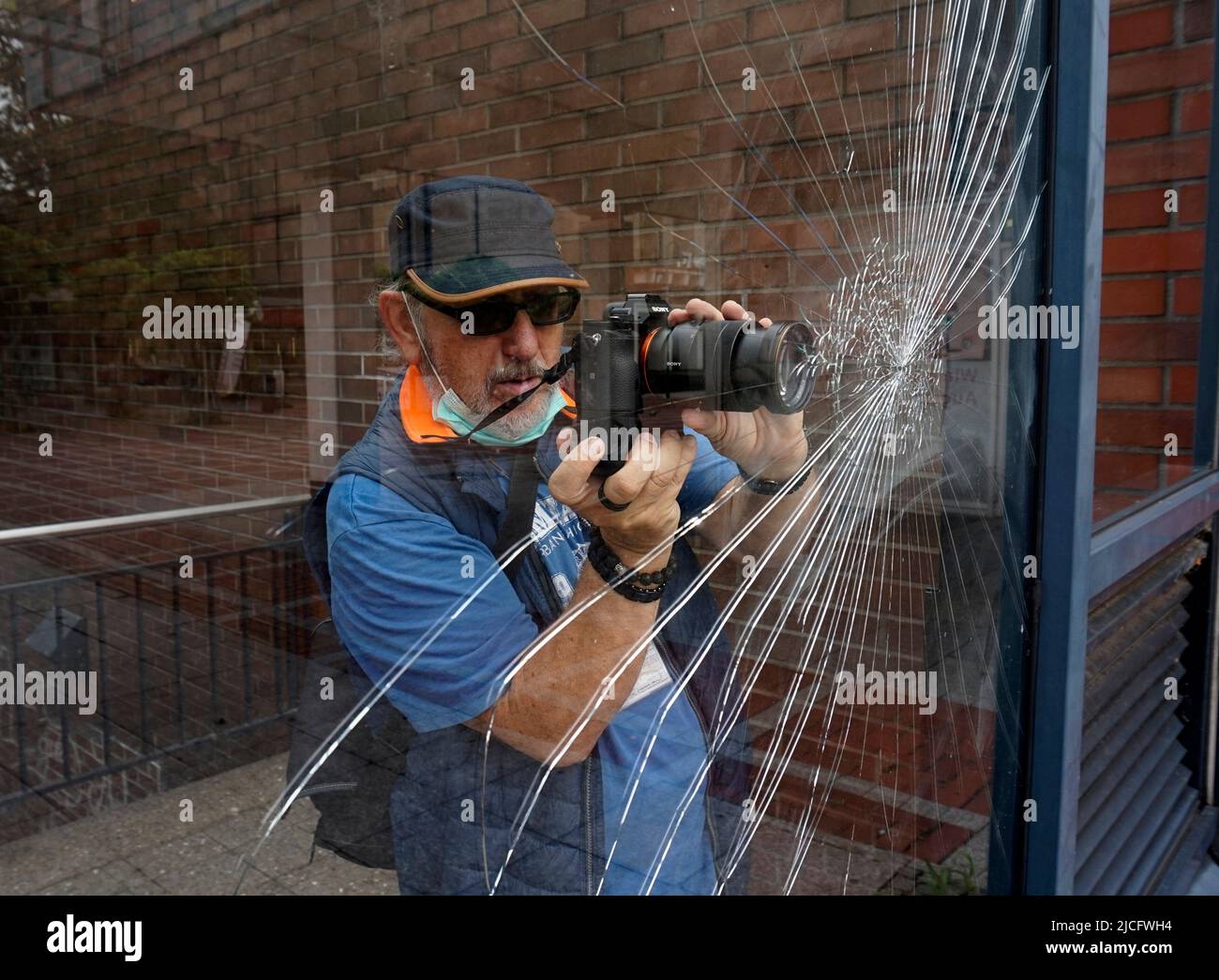 Leverkusen, Germany - Aug 17 2020 A photographer makes a photo from a damaged window. Clear case of vandalism. He uses a Sony alpha 7 mirror-less digi Stock Photo