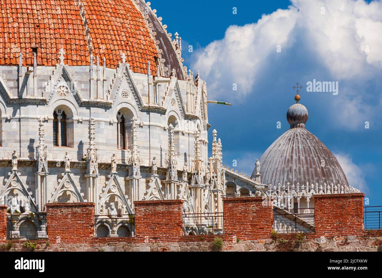 Pisa famous landmarks: Baptistry and Cathedral medieval domes, seen from outiside the city ancient walls, with blue sky and white clouds Stock Photo