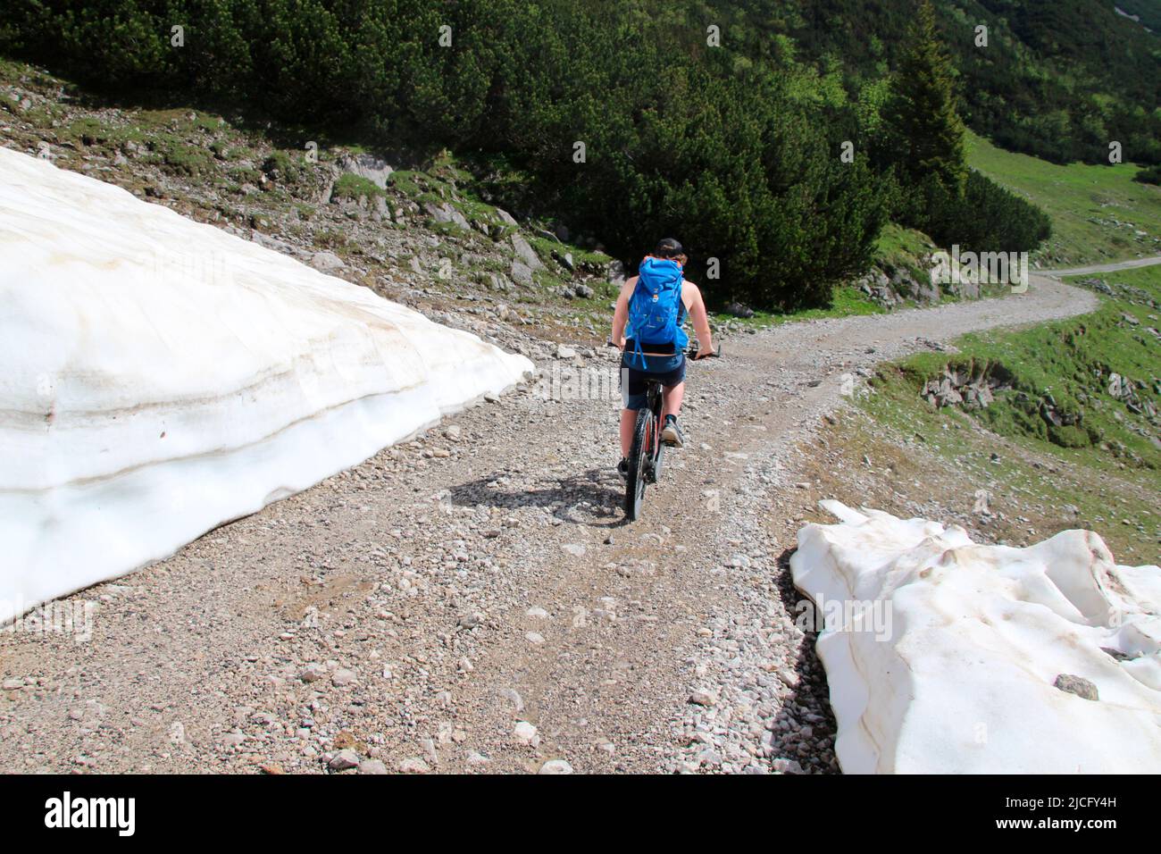 e-bike rider young man, shortly after the Karwendelhaus, in the direction of kleiner Ahornboden, on the side there is still the snow of the previous winter Stock Photo