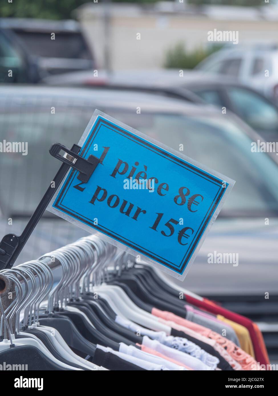 blue price tag on a clothes rack at a market showing the price per piece, 1 piece 8 euros and in French it says 2 for 15 euros Stock Photo