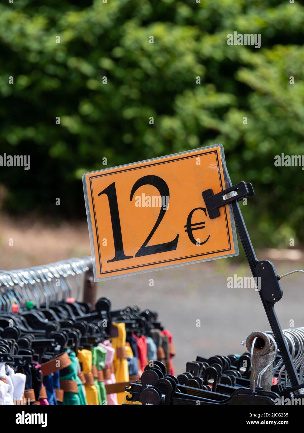 Orange sign on a clothes rack in a market indicating the price of 12 ...