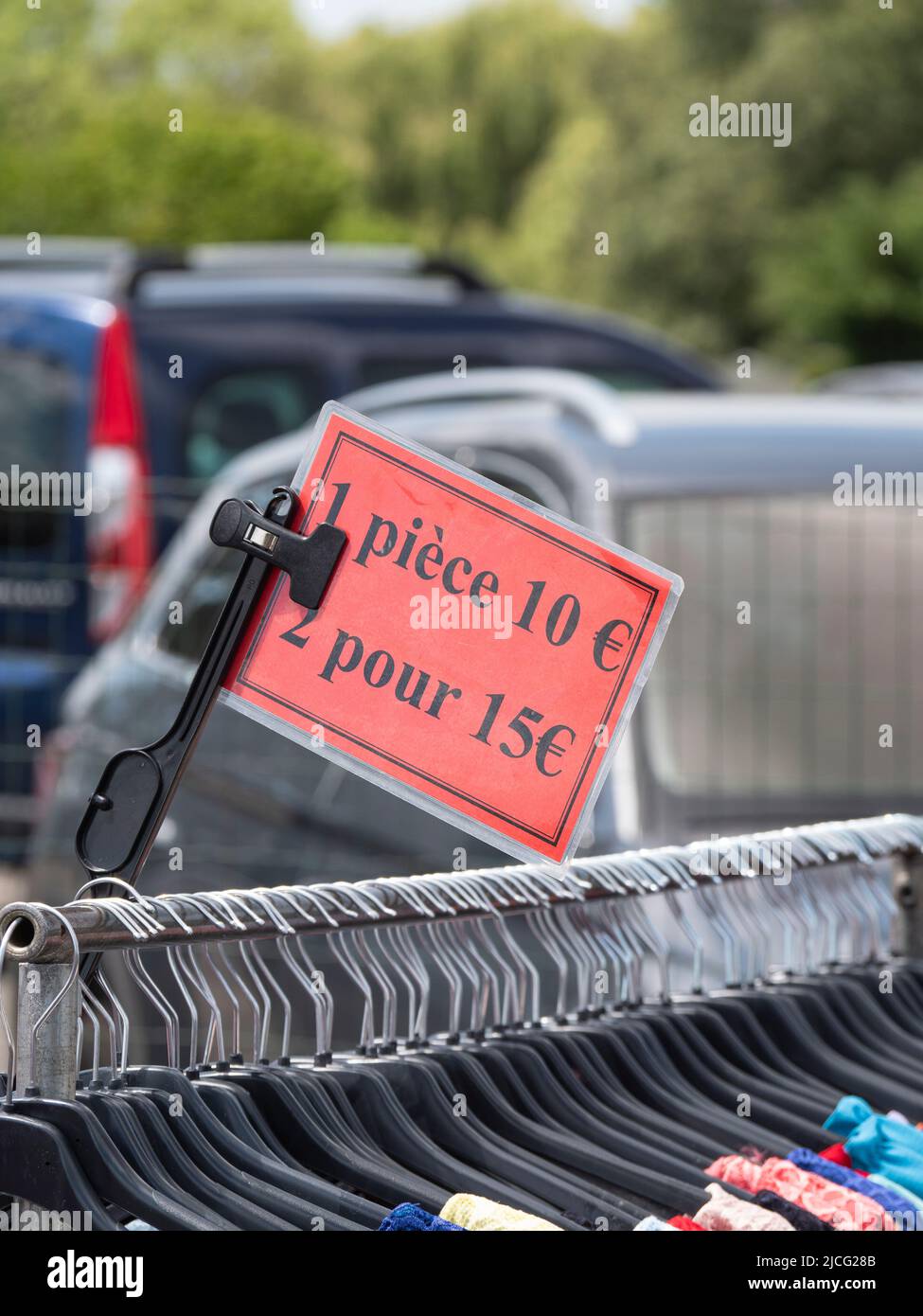 red price tag on a clothes rack at a market showing the price per piece, 1 piece 10 euros and in French it says 2 for 15 euros Stock Photo