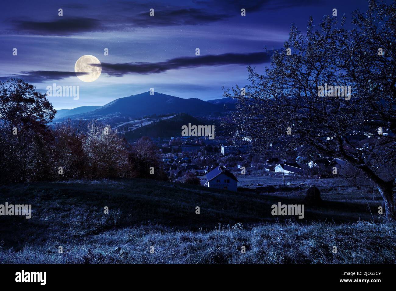 carpathian rural landscape in autumn at night. village in the valley at the foot of the mountain. beautiful countryside scenery in full moon light. tr Stock Photo