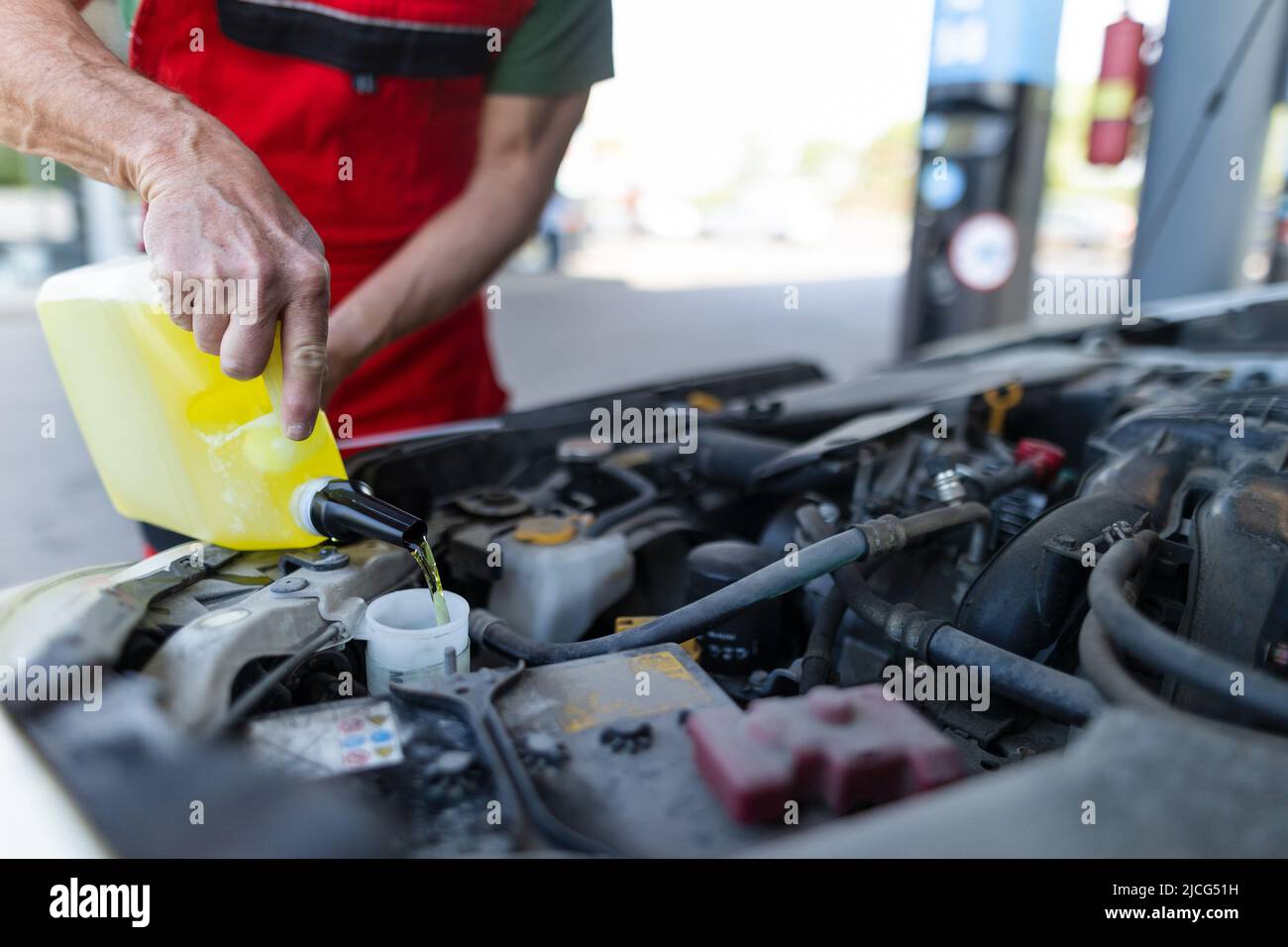 Car mechanic replacing and pouring oil into engine at maintenance