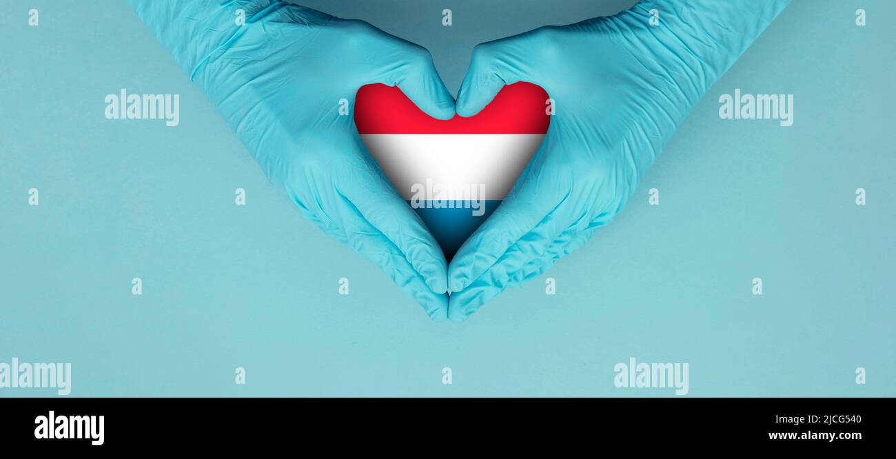 Doctors hands wearing blue surgical gloves making hear shape symbol with luxembourg flag Stock Photo