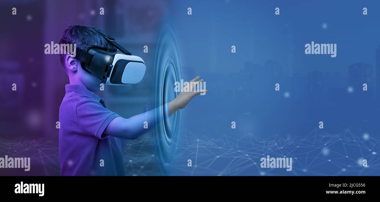 Boy with VR glasses from his room touches the metaverse with his hand. Copy space on blue background Stock Photo