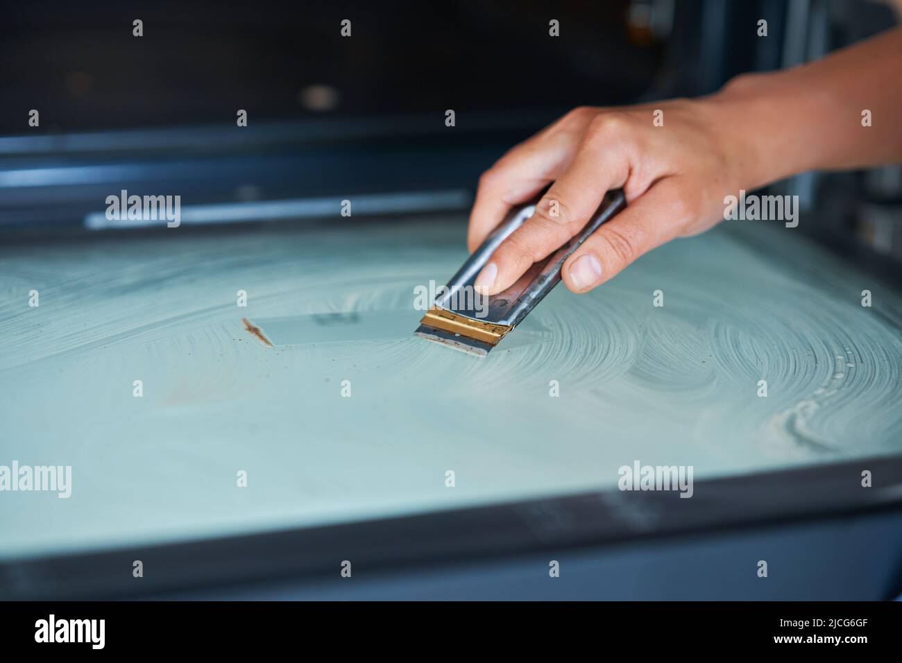 Young woman cleaning oven in the kitchen Stock Photo