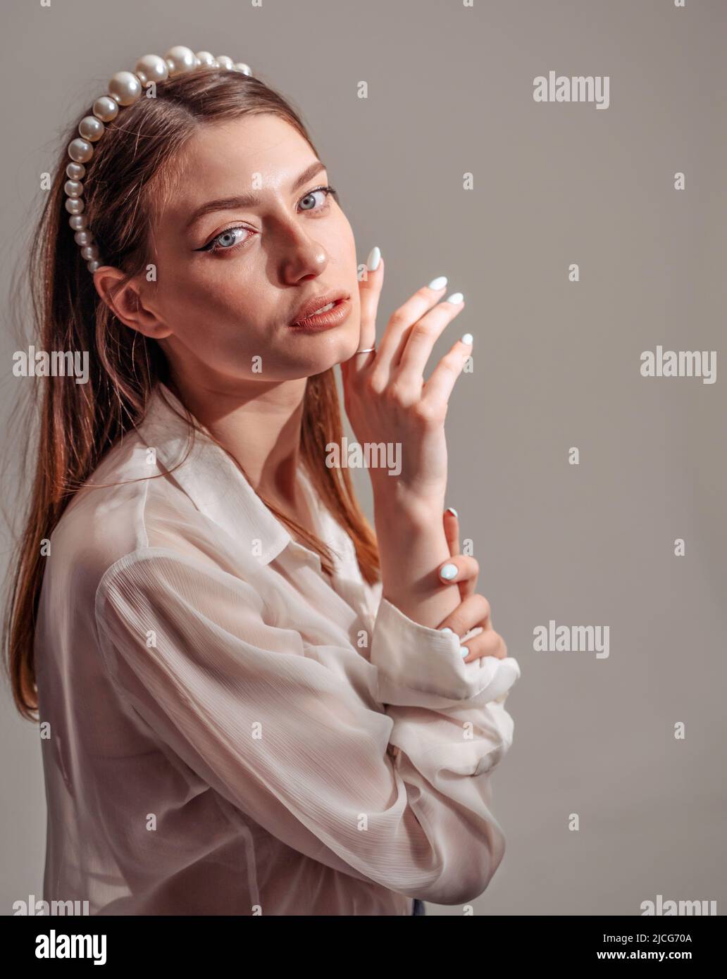 Stylish young woman in white casuals looking away and smiling. vertical Stock Photo
