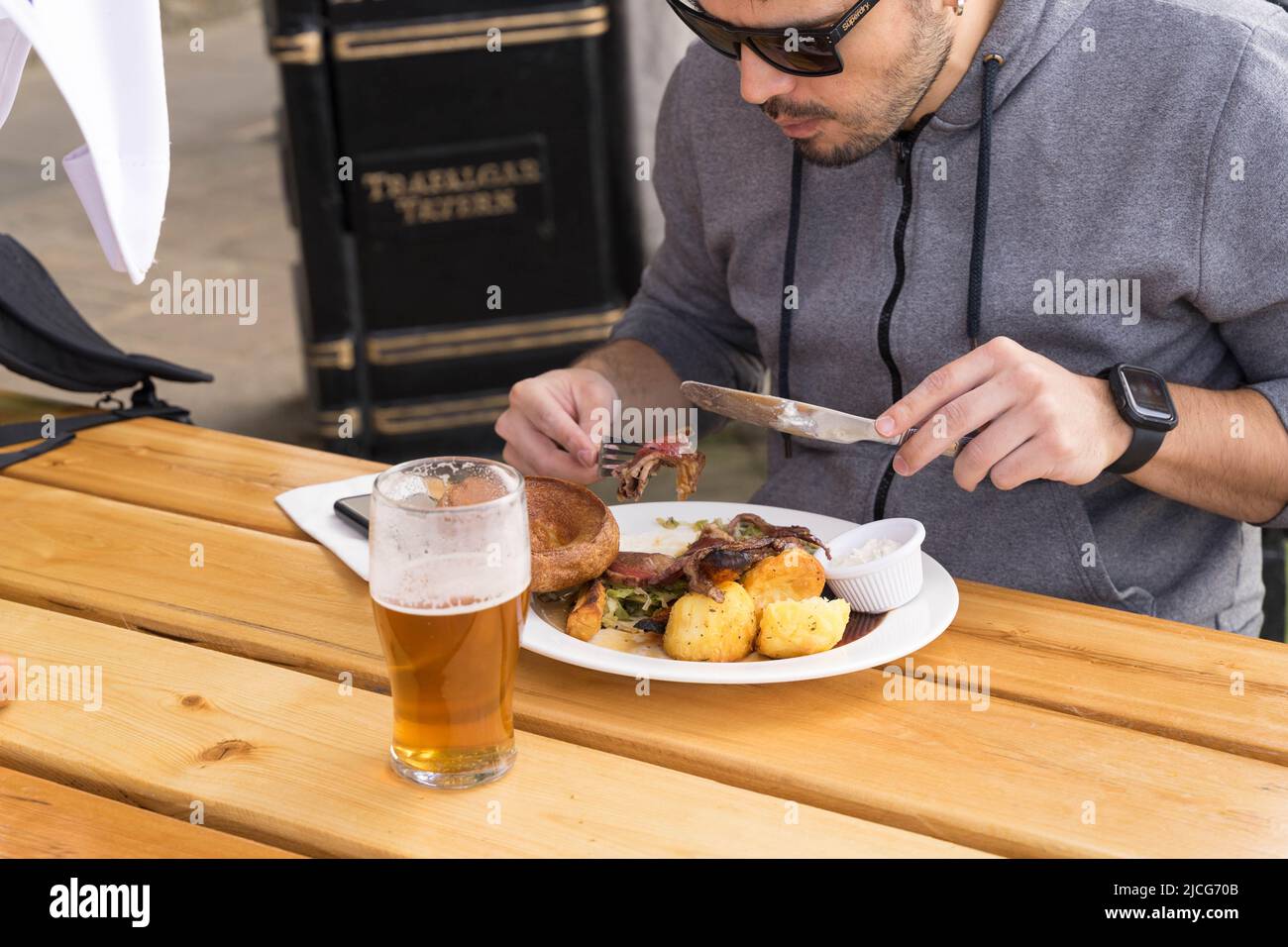 a man enjoys a hearty Sunday roast lunch with a pint of beer Greenwich