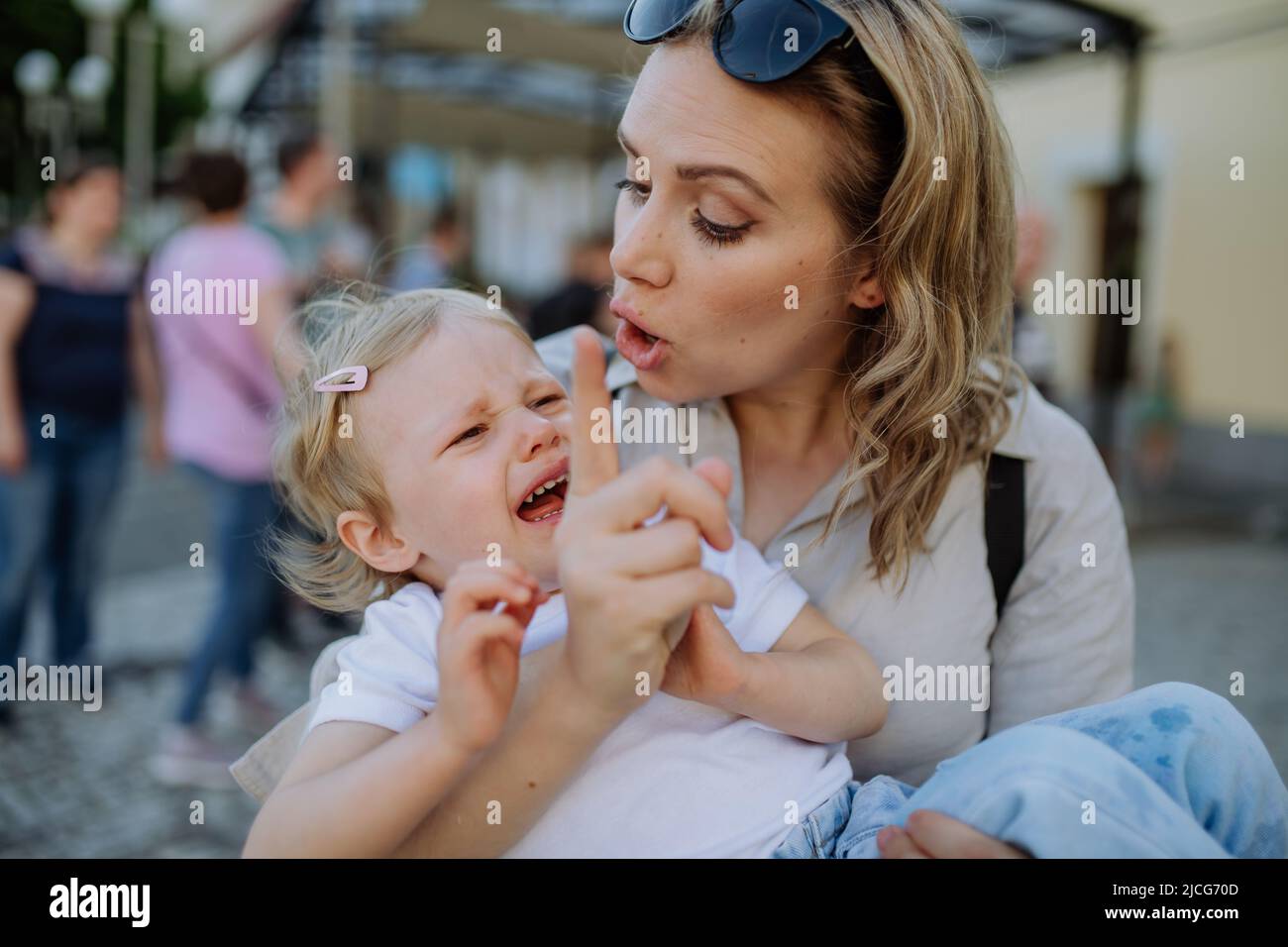 Mother scolding her little daughter in street. Child is crying and woman is shaking finger because of child's bad behavior. Stock Photo