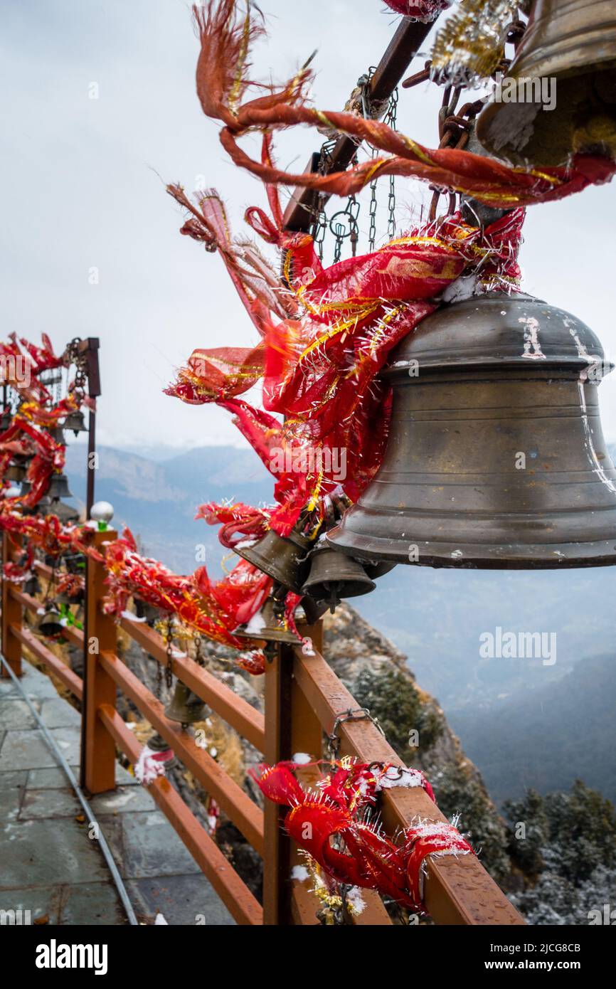 A closeup shot of hanging bells with holy red cloths with a snow covered mountains in the Background, Kartik Swami Temple, Rudraprayag Uttarakhand ,In Stock Photo