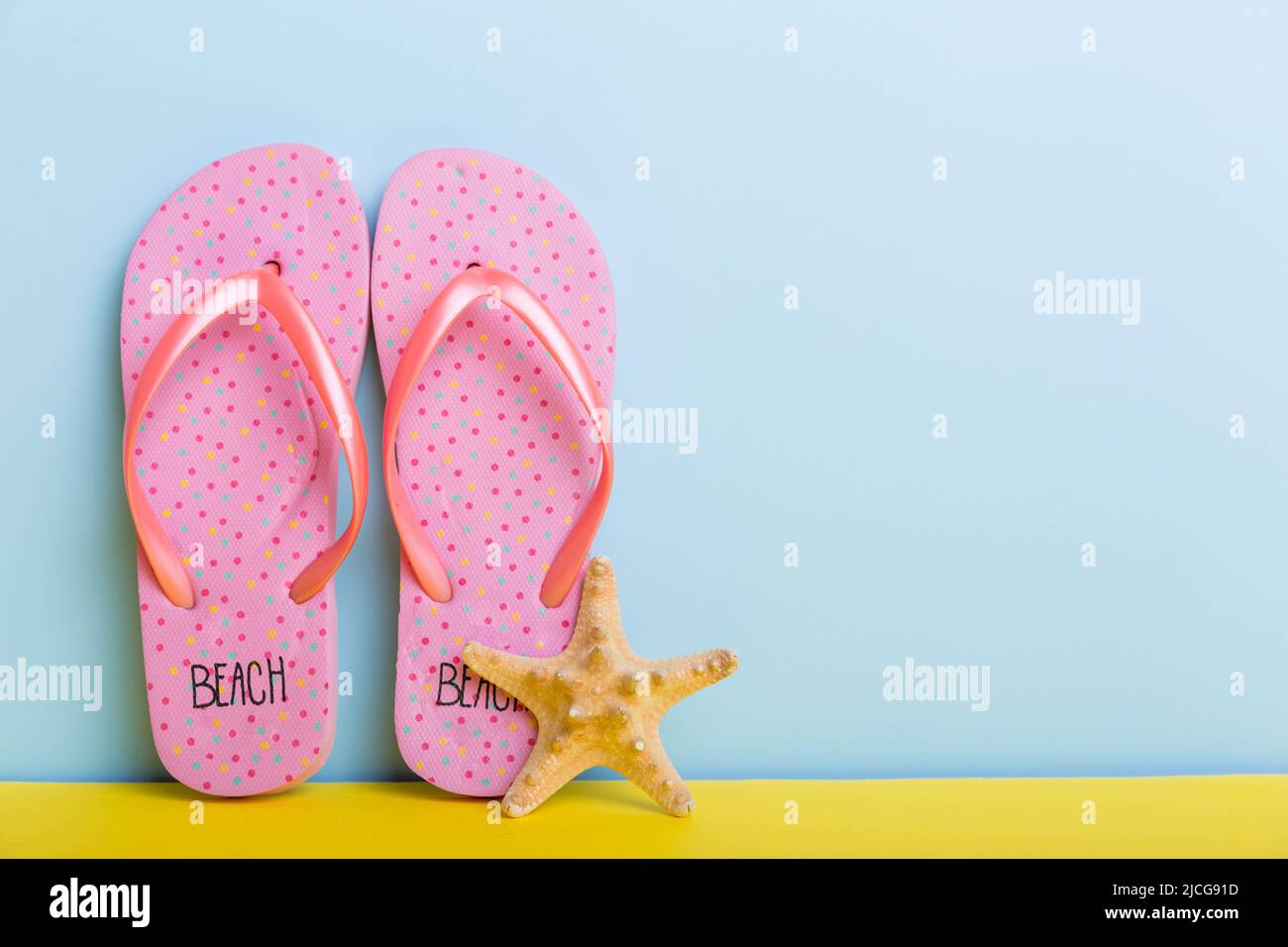 Beach accessories. Flip flops and starfish on colored background. Mock ...