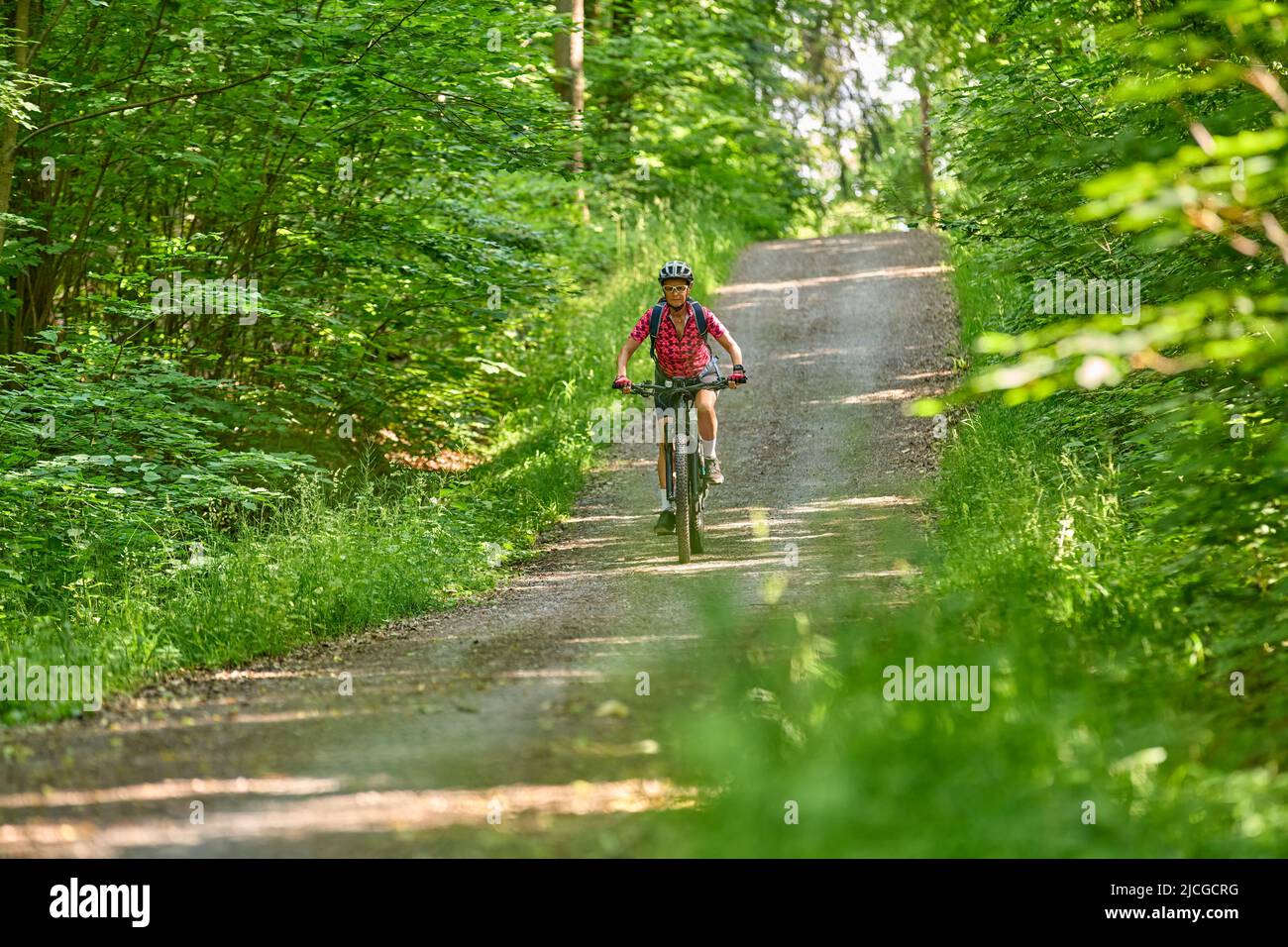 nice active senior woman riding her electric mountain bike in the green city forest of Stuttgart, Germany Stock Photo