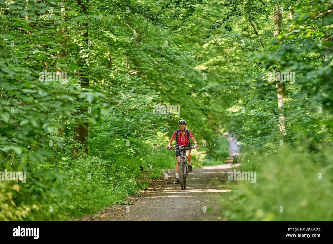 nice active senior woman riding her electric mountain bike in the green ...