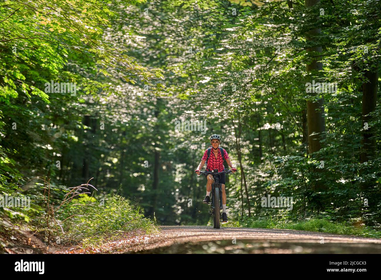 nice active senior woman riding her electric mountain bike in the green ...