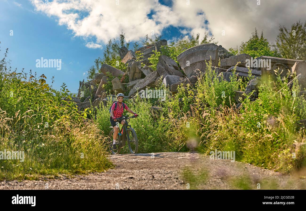 active senior woman with electric mountain bike on tour to Mount Birkenkopf, a summit built from WW II debris, high above city of Stuttgart, Germany Stock Photo