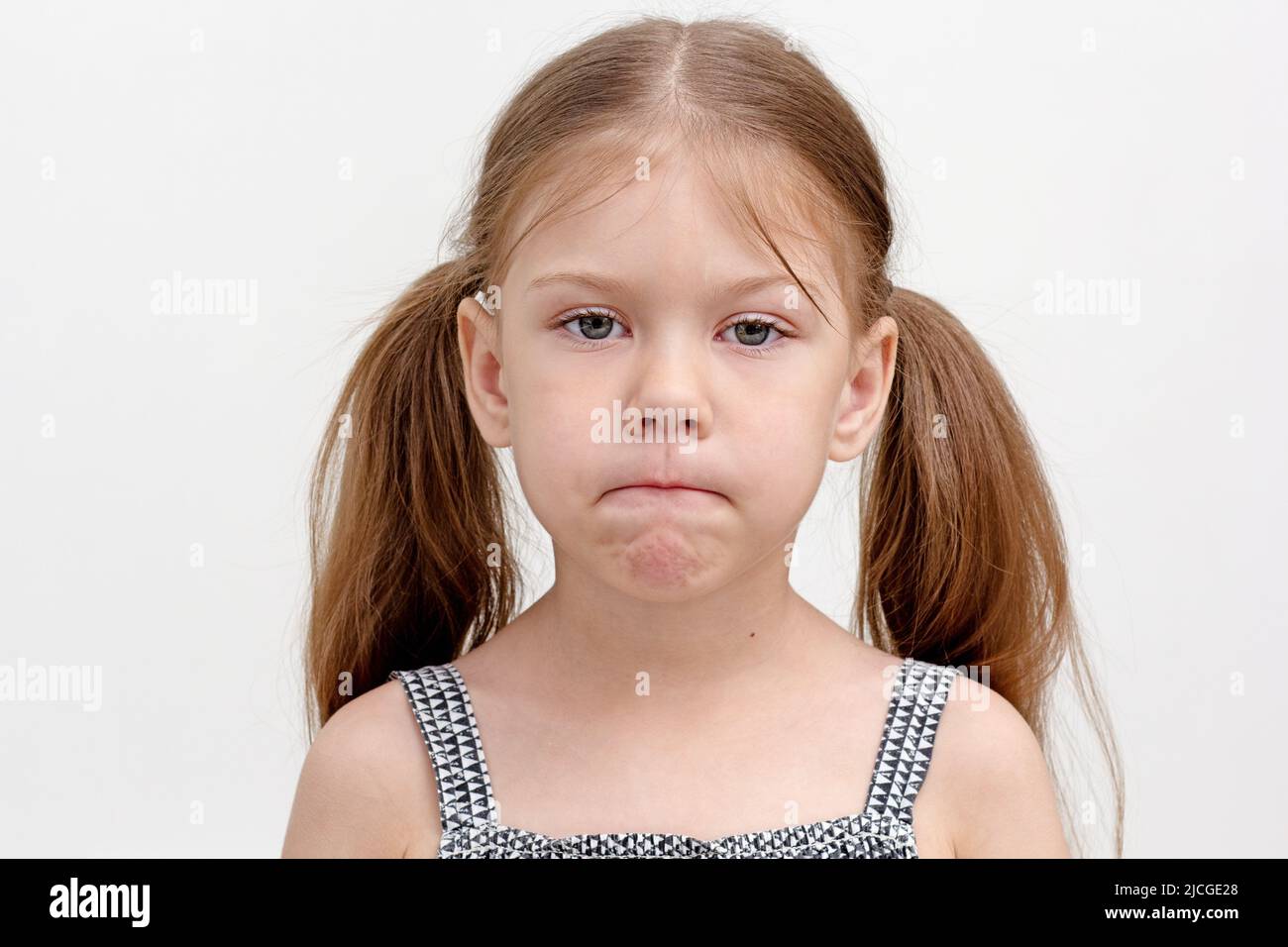 Caucasian little girl of 6 years pursing tense lips which are overly tight and difficult to move. Concept dysarthria, logopedics Stock Photo