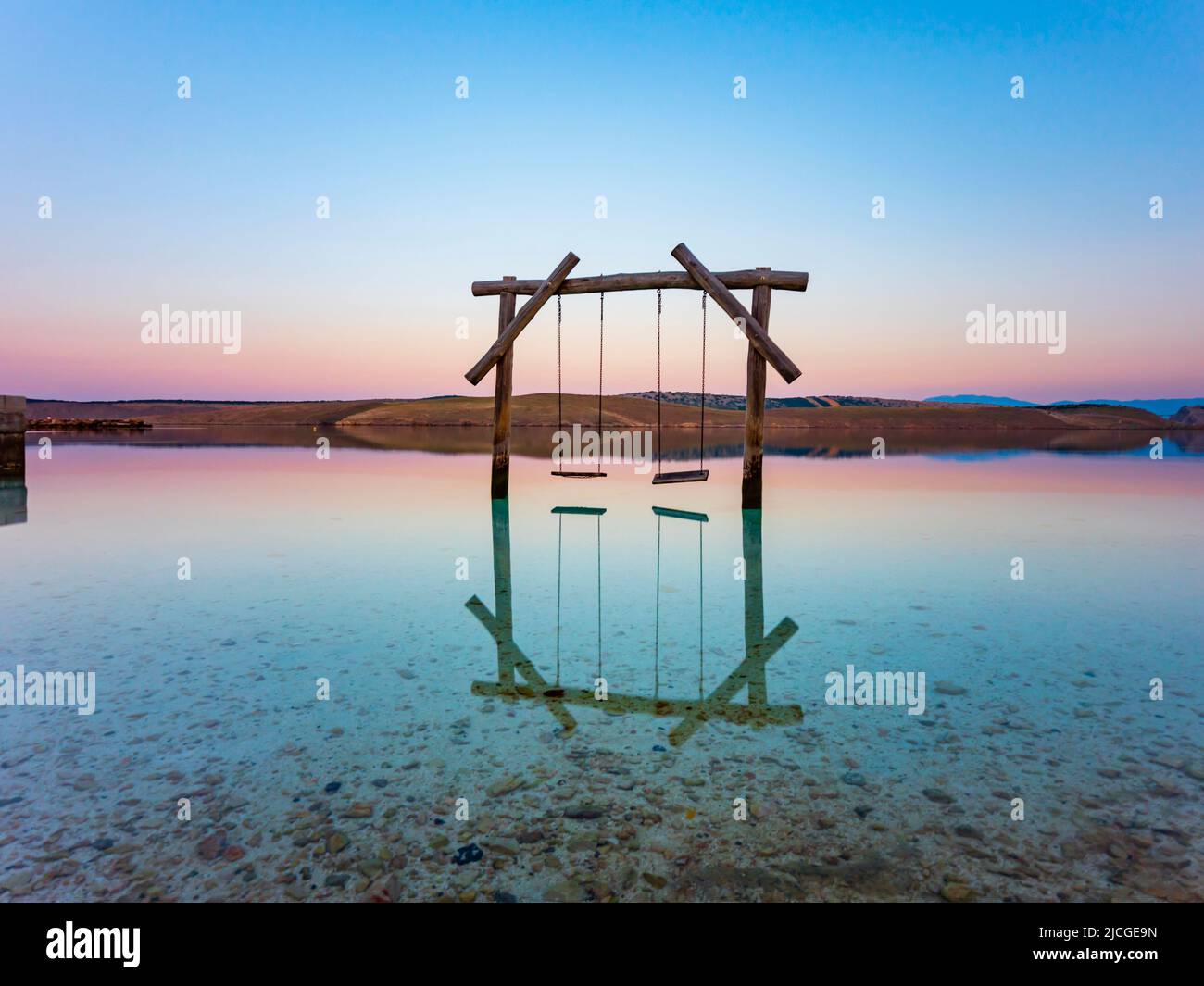 Empty swings dawn seaside scenery calm surface of sea near coast beach coastline, Jadranovo in Croatia Europe Stock Photo