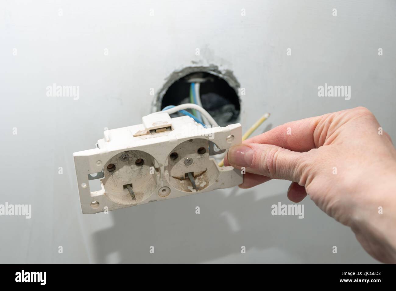 Installation of new electrical wiring, plastic socket and electric wires for future sockets on a plastered wall. Hand installing a new socket. DIY hou Stock Photo