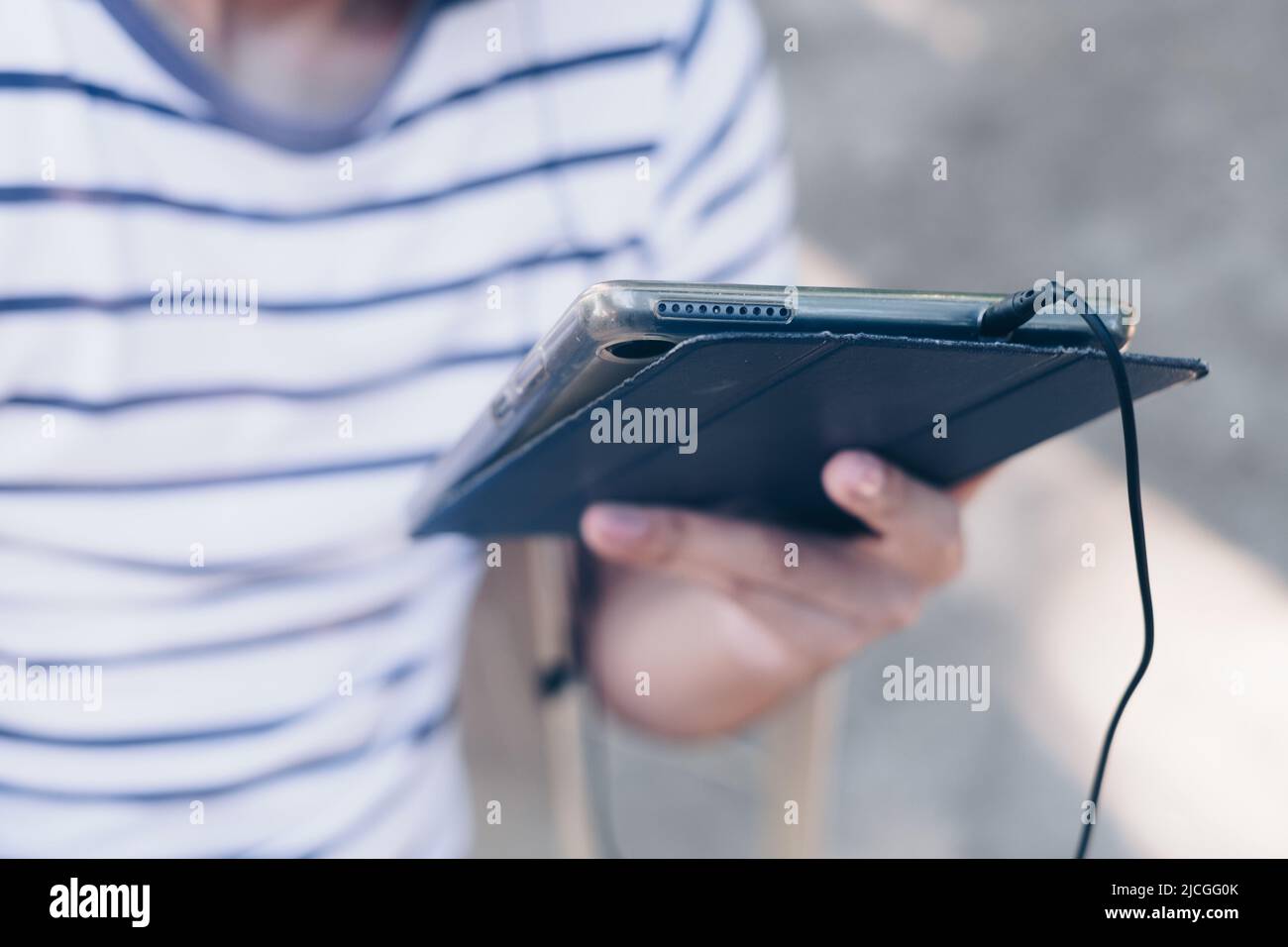 Young boy's left hand holding an electronic tablet. Selective focus. Stock Photo