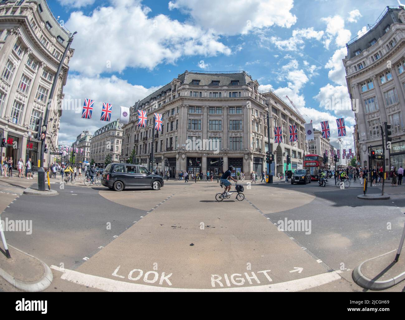Oxford Street, London, UK. 13 June 2022. Platinum Jubilee flags hang above the shopping streets around Oxford Circus on a warm day in this fisheye lens view. Credit: Malcolm Park/Alamy Live News. Stock Photo