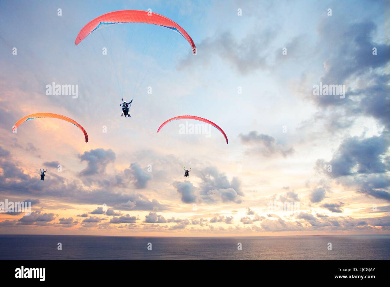 Three paragliders against the sky over with beautiful sunset Stock Photo