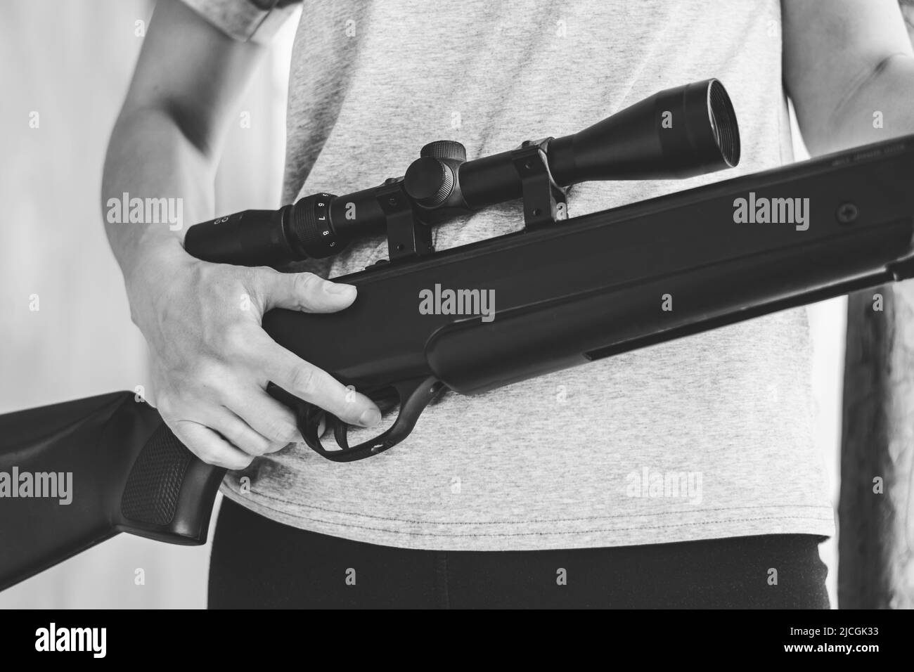 A woman is holding a large sniper rifle, close-up. A young woman with a gun in her hands. Air rifle with optical sight Stock Photo