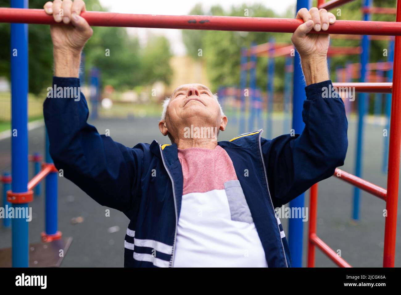 Sportive old man doing pull-ups outdoors Stock Photo