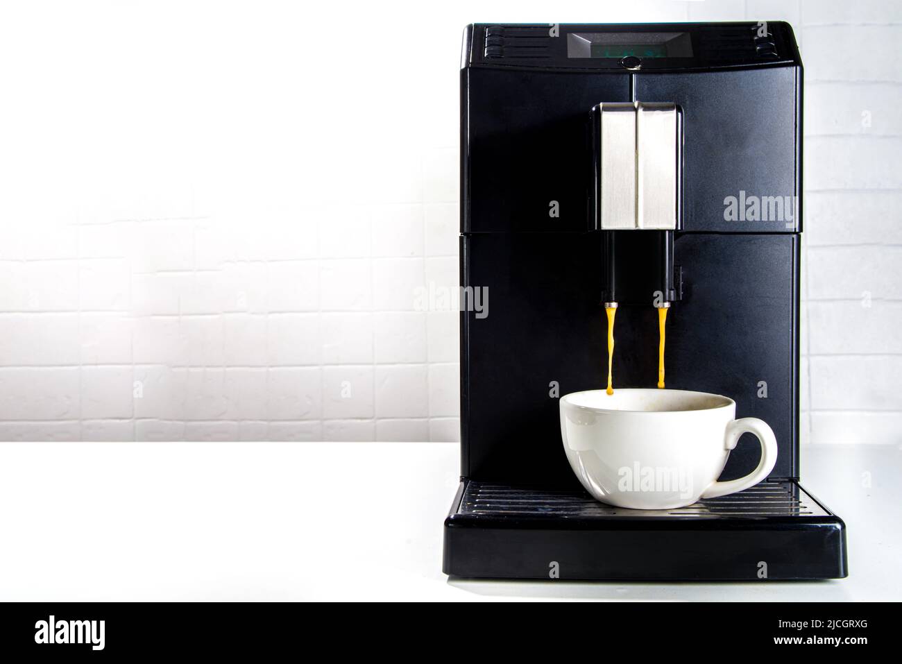 Freshly brewed coffee is poured from the coffee machine into white