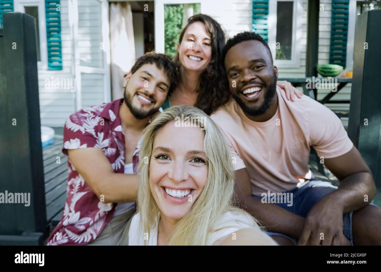 Multiethnic young friends taking selfie outdoor - Young people having fun at summer house - Focus on center girl face Stock Photo