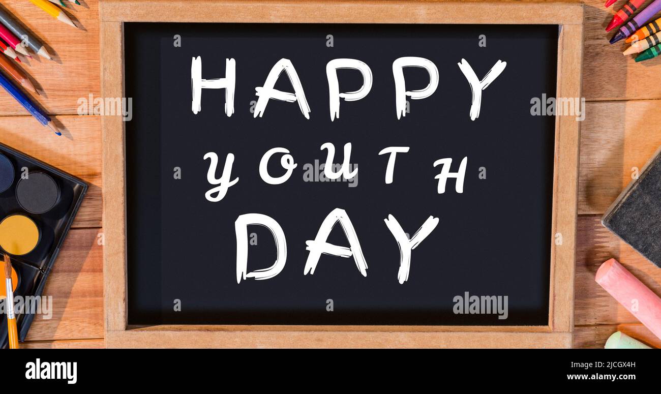 Writing slate with happy youth day text with colored pencils, watercolor paints, crayons on table Stock Photo