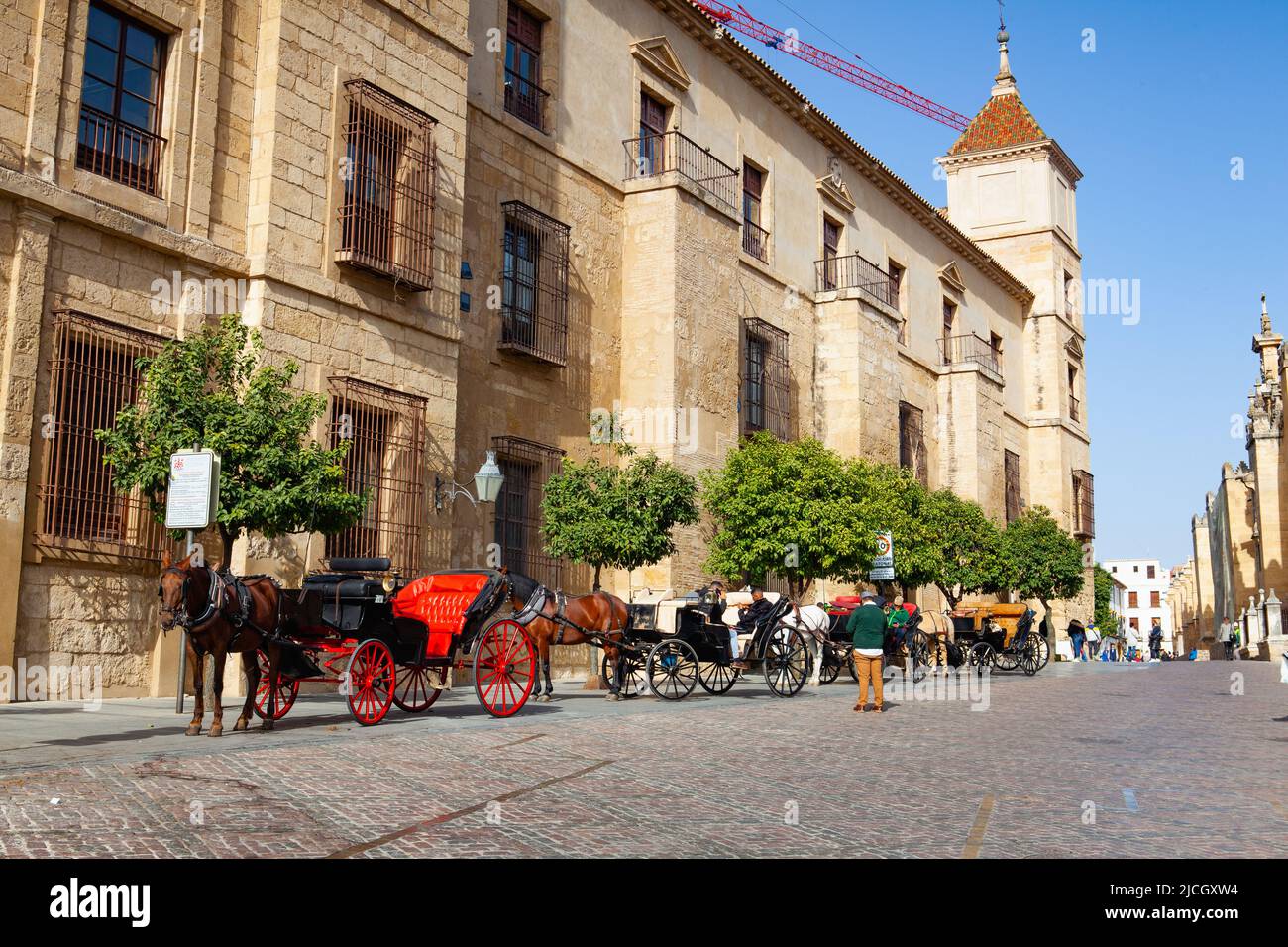 Cordoba, Spain - February 11,2022: Red horse carriage parked next to the mosque of Cordoba, Andalusia, Spain. Horse and sleigh ride on Cordoba street. Stock Photo