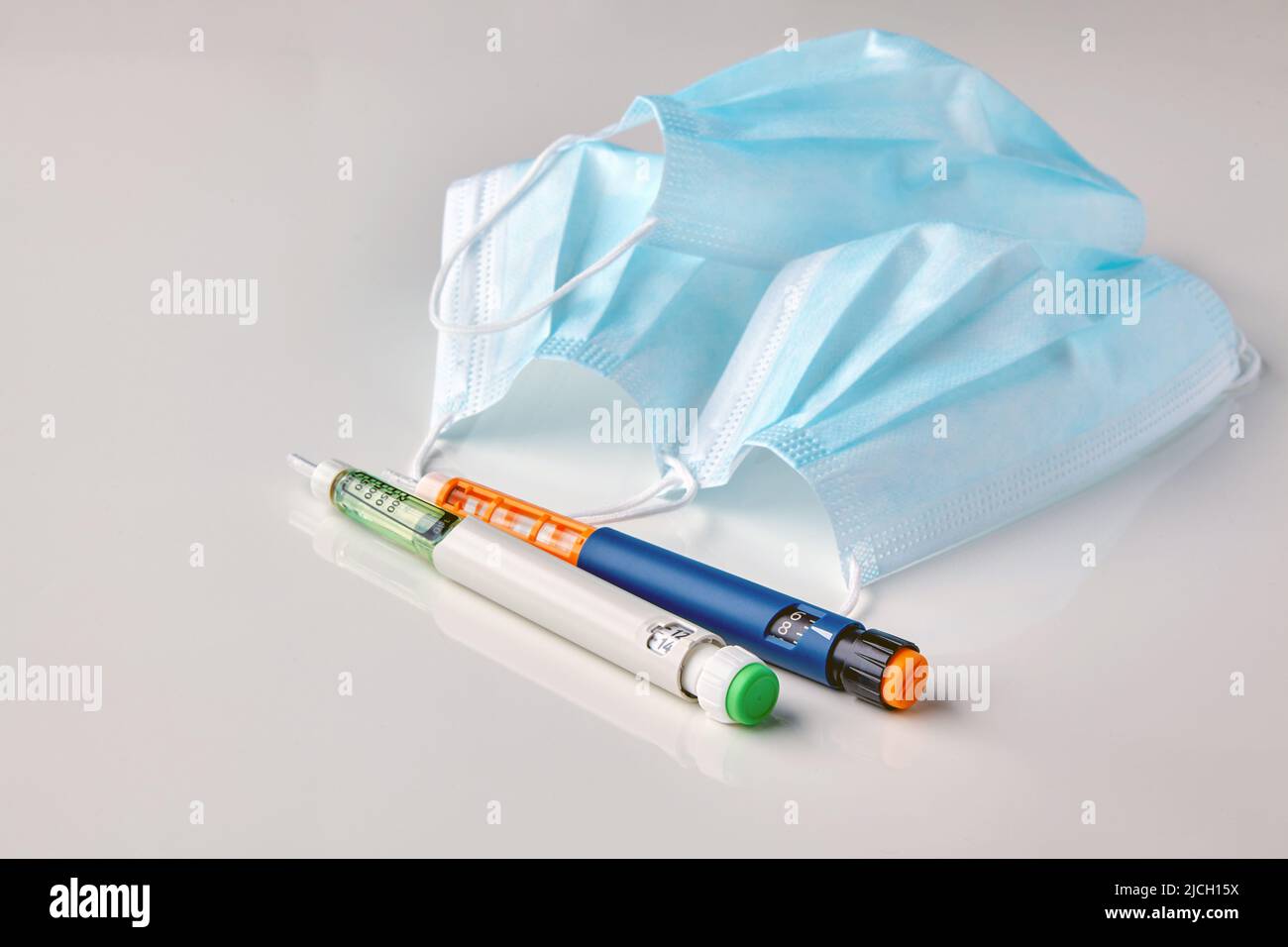 Insulin syringe pens and medical masks on a white table. The need to