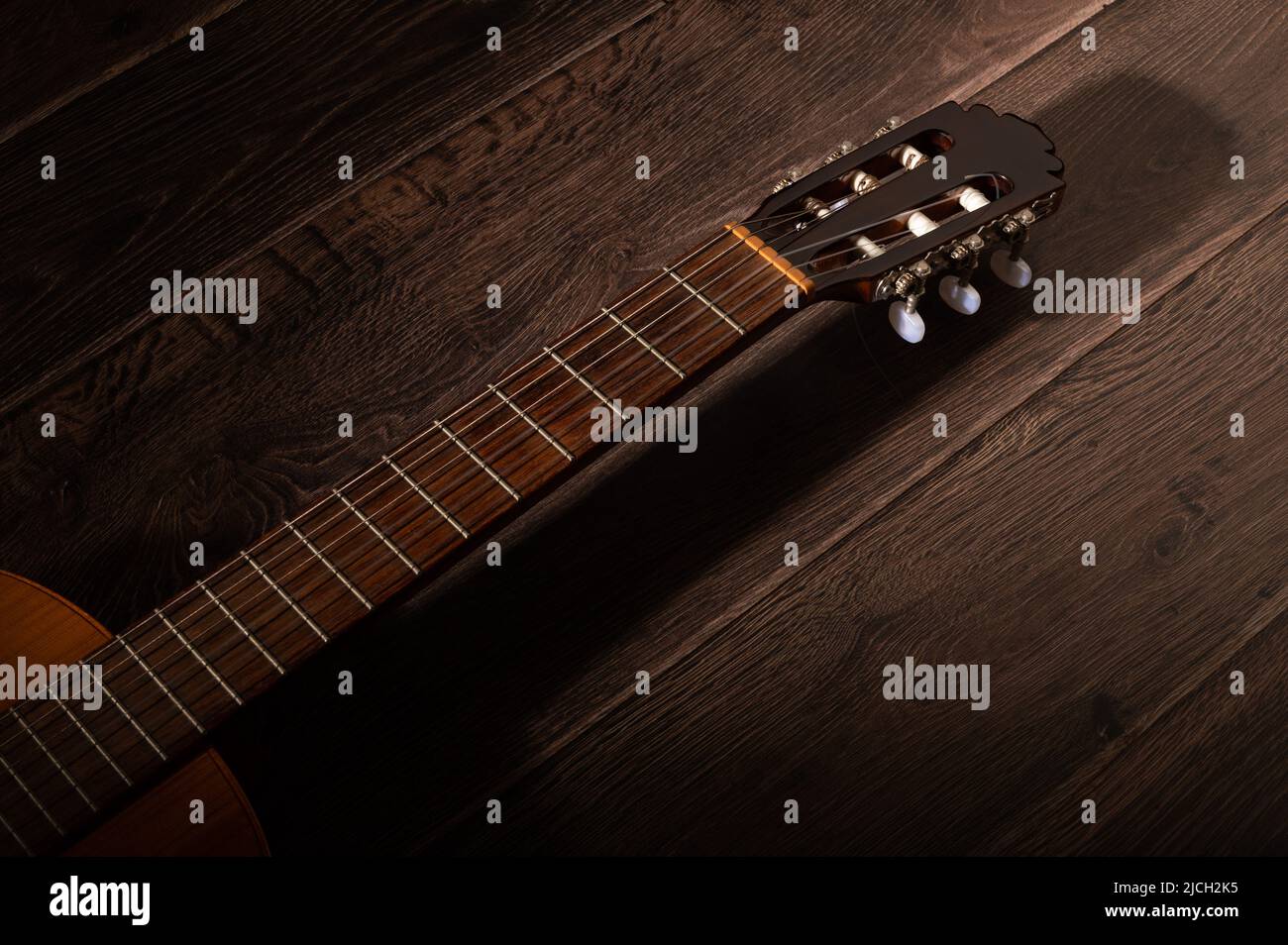 Classical guitar fretboard and machine head on a dark wood background