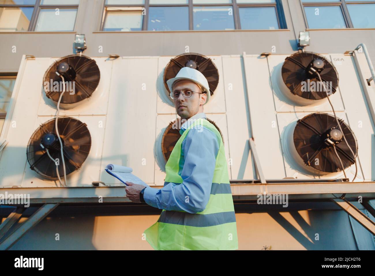 Service engineer in uniform inspecting industrial refrigeration system