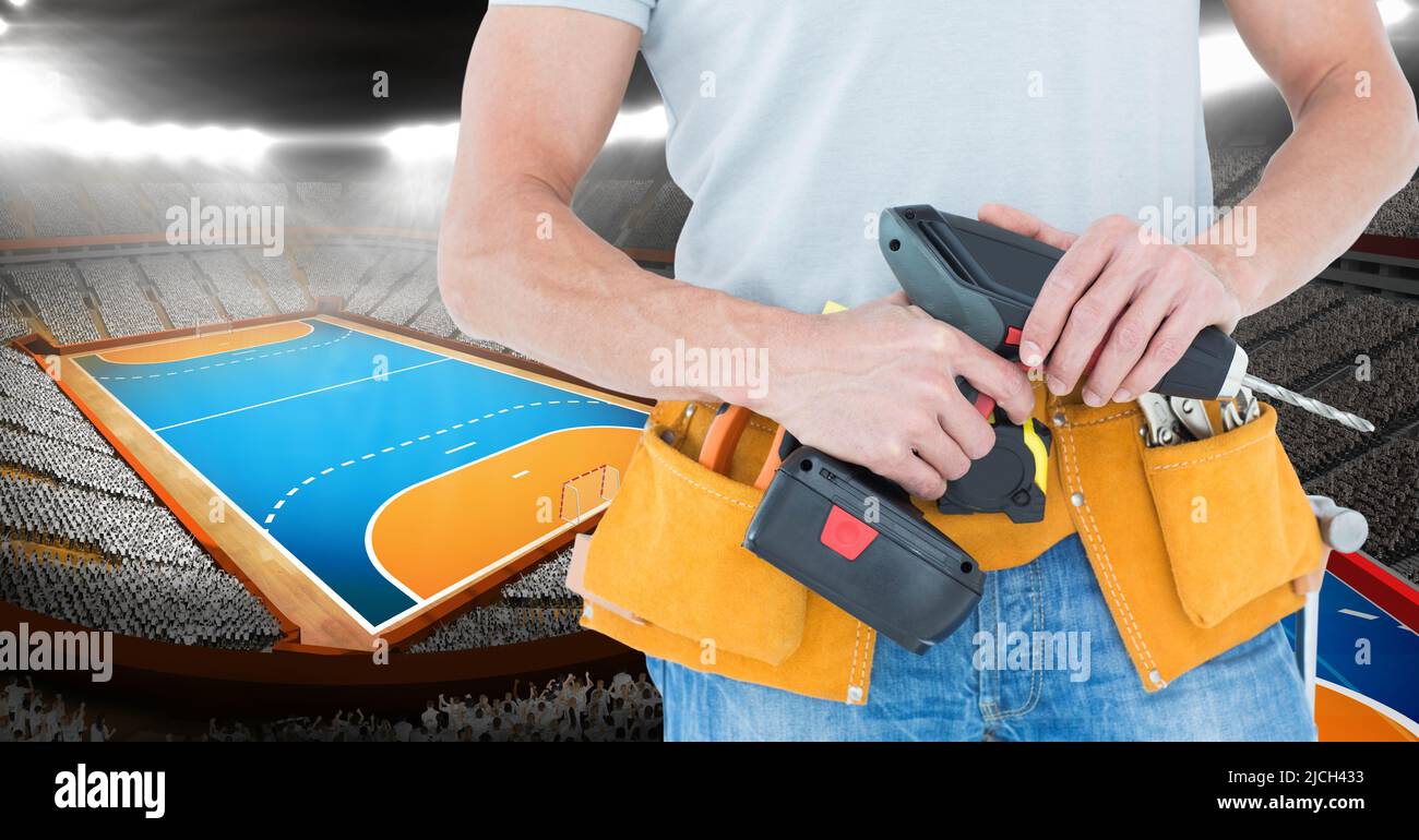 Mid section of caucasian male worker with drilling machine against sports stadium with copy space Stock Photo