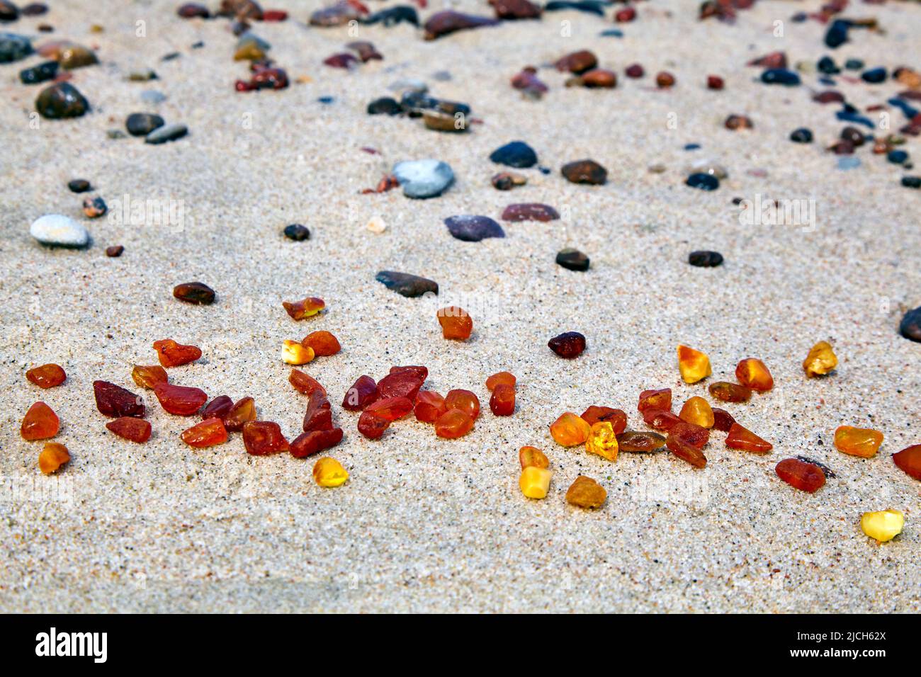 Amber in the sand. Amber on the seashore. Sun stone Stock Photo - Alamy