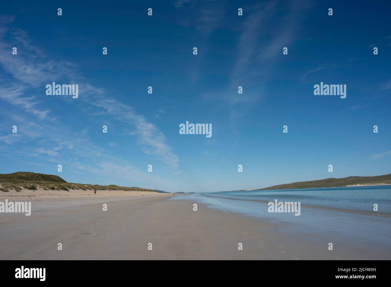 Luskentyre beach with sea and sand dunes. People on beach. Blue sky and light clouds, lots of copy space. Stock Photo
