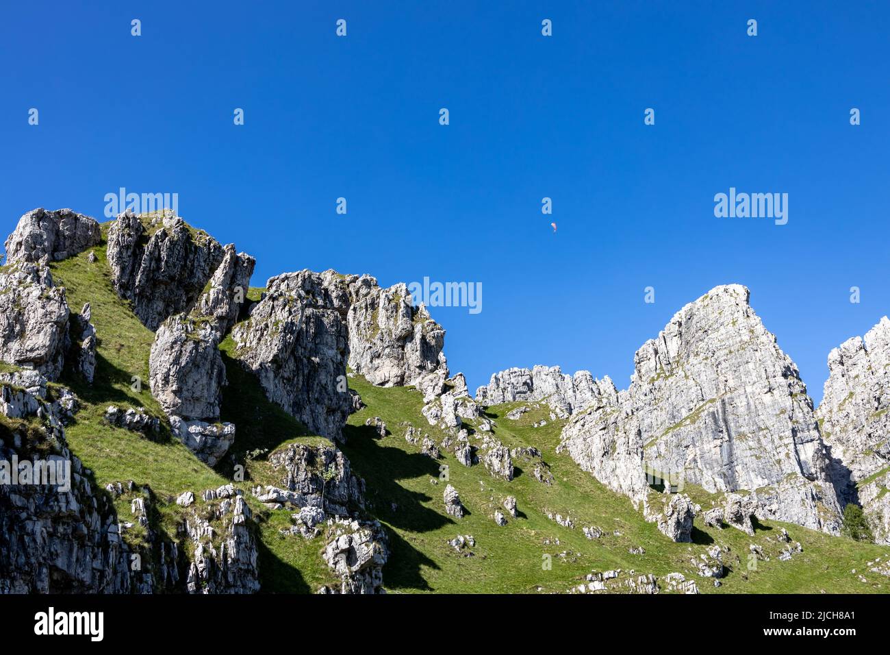 beautiful Italian Dolomites mountains with paraglider flying in the blue sky Stock Photo