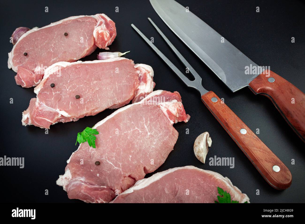 Raw veal meat fillet for grilling with seasoning and utensils, Tenderloin fillet mignon with meat knife and ingredients for cooking on dark background Stock Photo