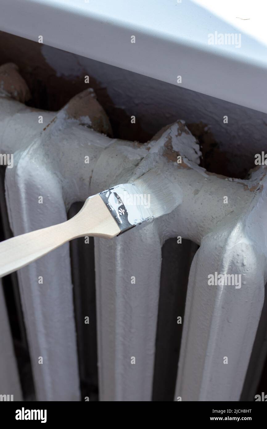 Painting radiators with a special brush. Battery painting Stock Photo