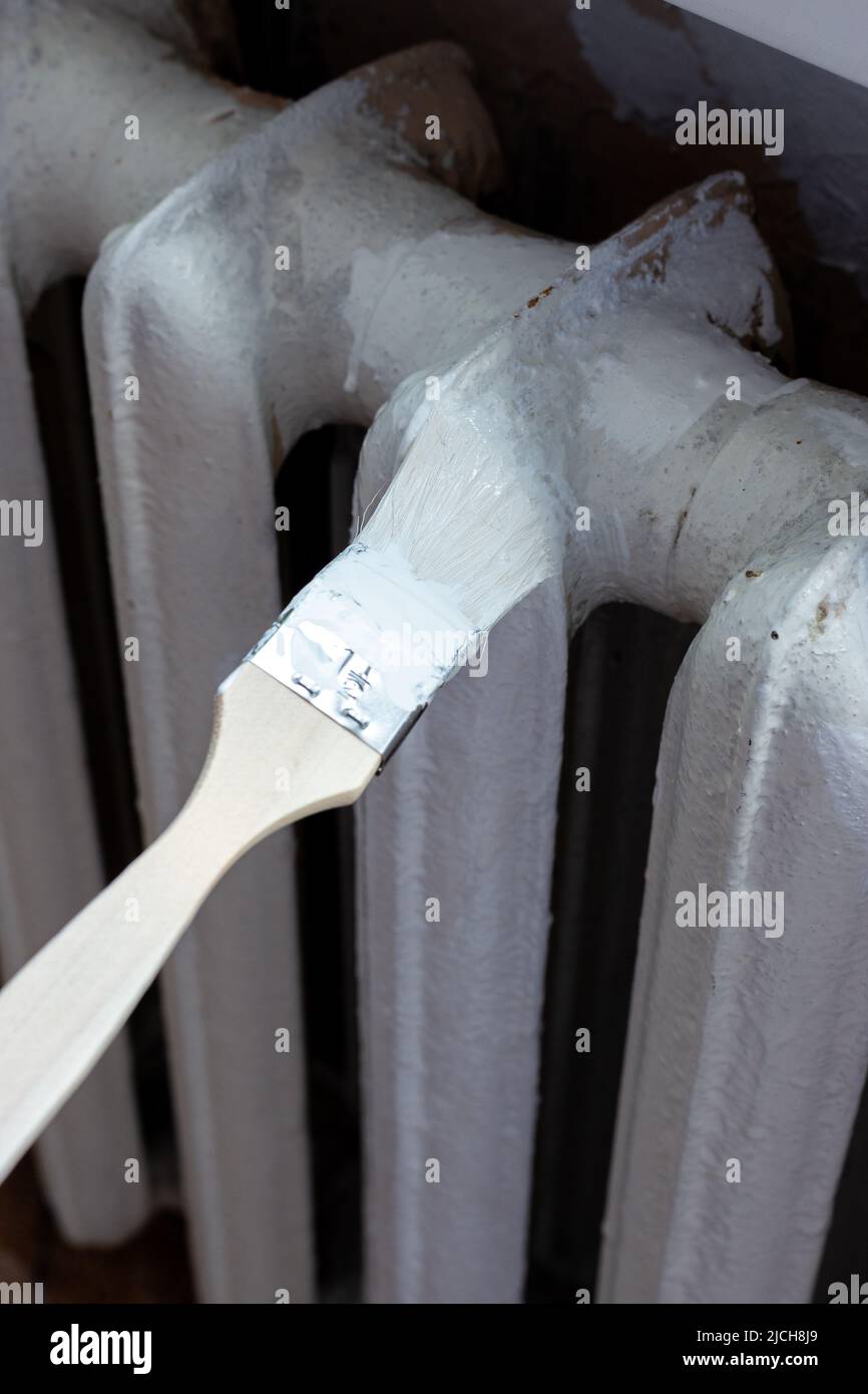 Painting radiators with a special brush. Battery painting Stock Photo