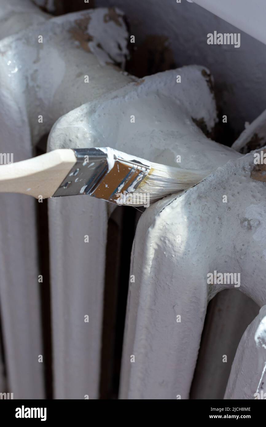 Painting radiators with a special brush. Battery painting Stock Photo