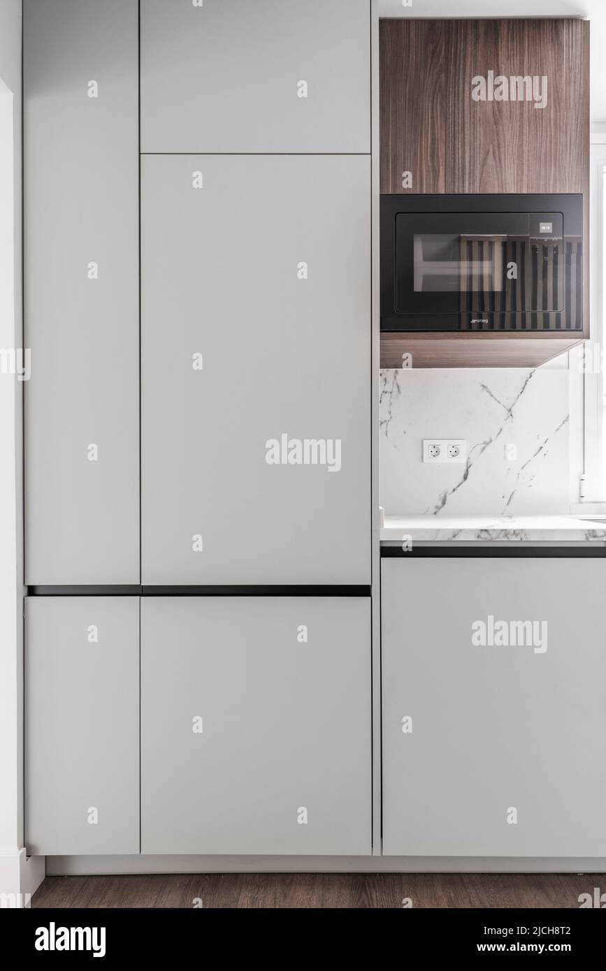 Front of a kitchen with white wooden furniture combined with wood