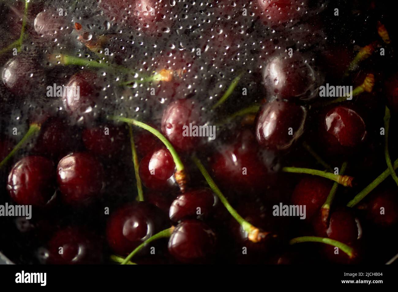 Juicy cherries or cherries in the water under the fogged glass. Vitamins and berries. Juiciness. Stock Photo