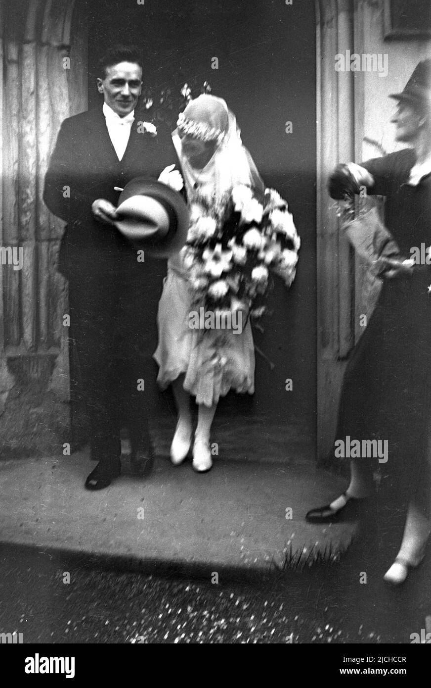 1930s, historical, a just married couple, coming out of the church, bride ducking her head slightly to avoid the confetti, USA. Stock Photo
