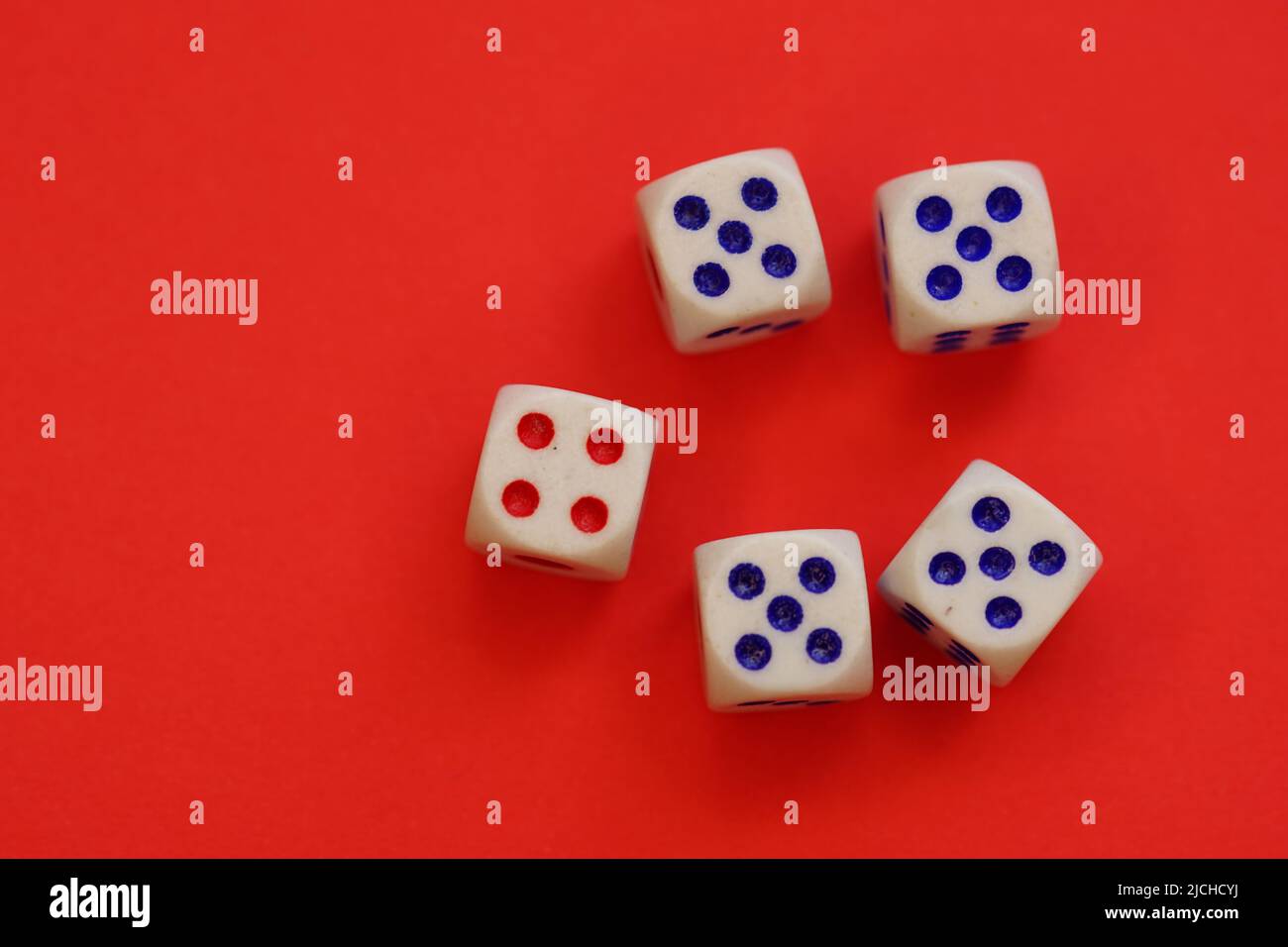 Dices with different numbers on a red table. Stock Photo