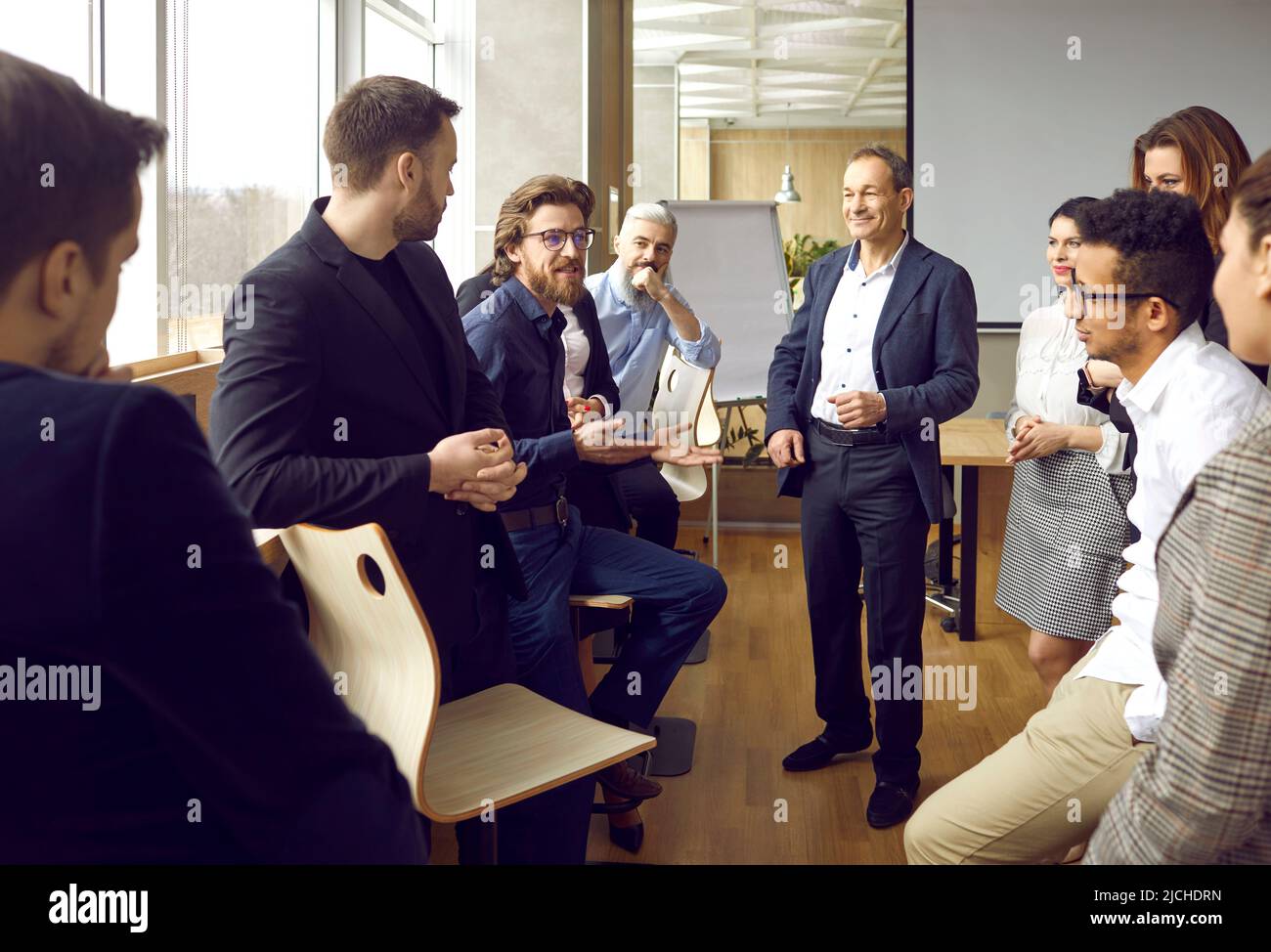 Business people communicate and joke in casual conversation at briefing in loft coworking office. Stock Photo