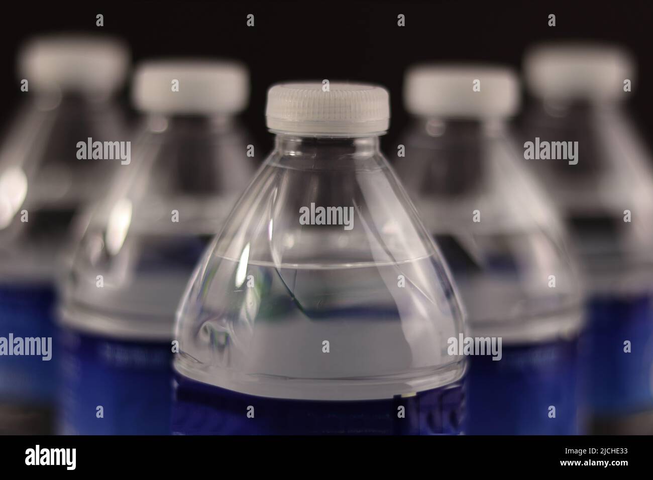 https://c8.alamy.com/comp/2JCHE33/small-water-bottles-placed-in-perspective-view-and-on-a-black-background-2JCHE33.jpg