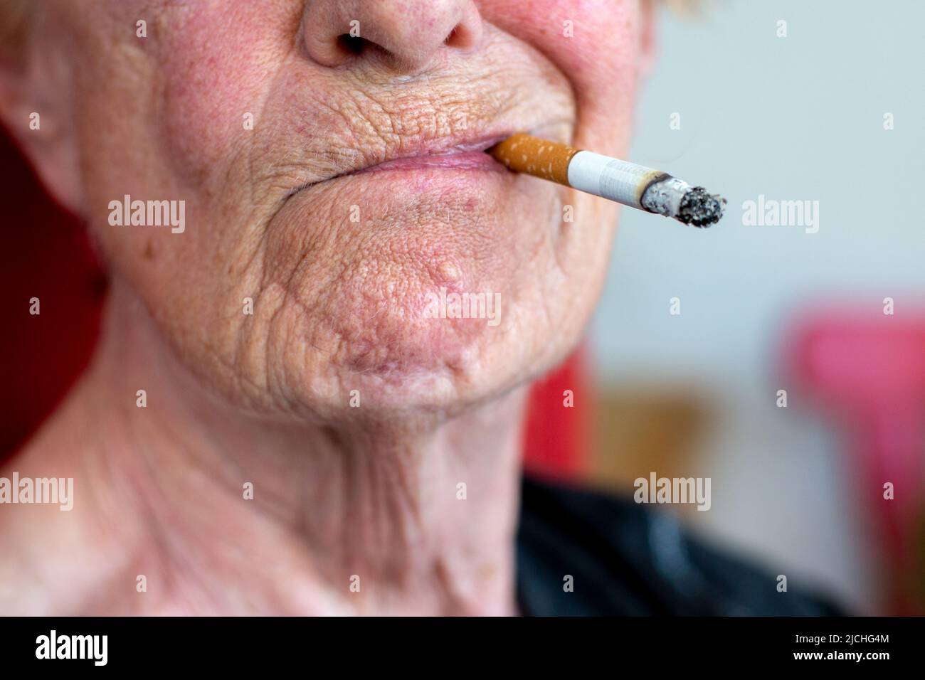 close-up of an wrinkled old woman smoking a cigarette Stock Photo